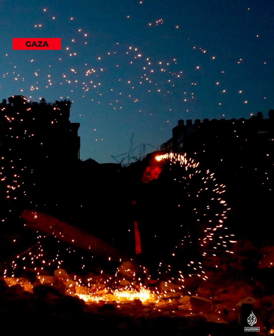 a man twirling sparkler fireworks in the rubble of a bombed building