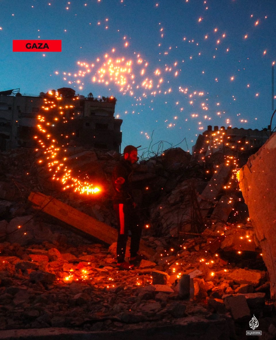 a man twirling sparkler fireworks in the rubble of a bombed building