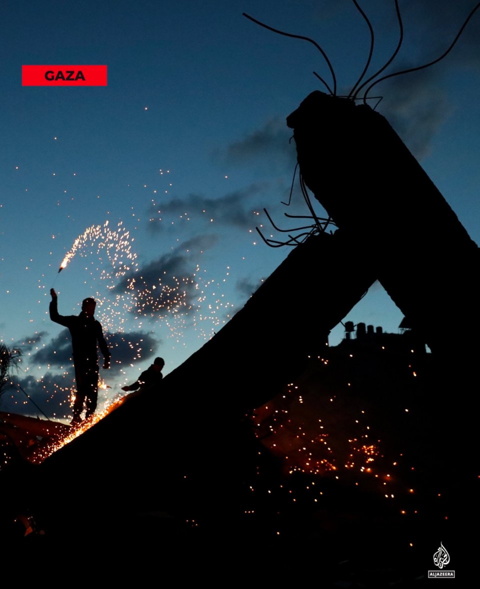 a man twirling sparkler fireworks in the rubble of a bombed building