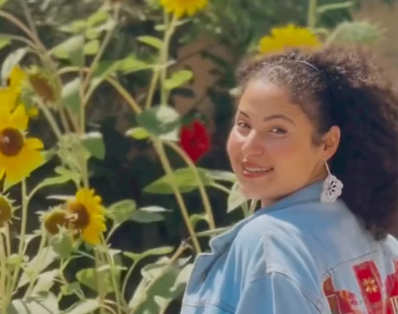 a picture of wizard bisan wearing a jean jacket in front of sunflowers